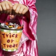 a child in a pink costume holding a trick or treat bucket